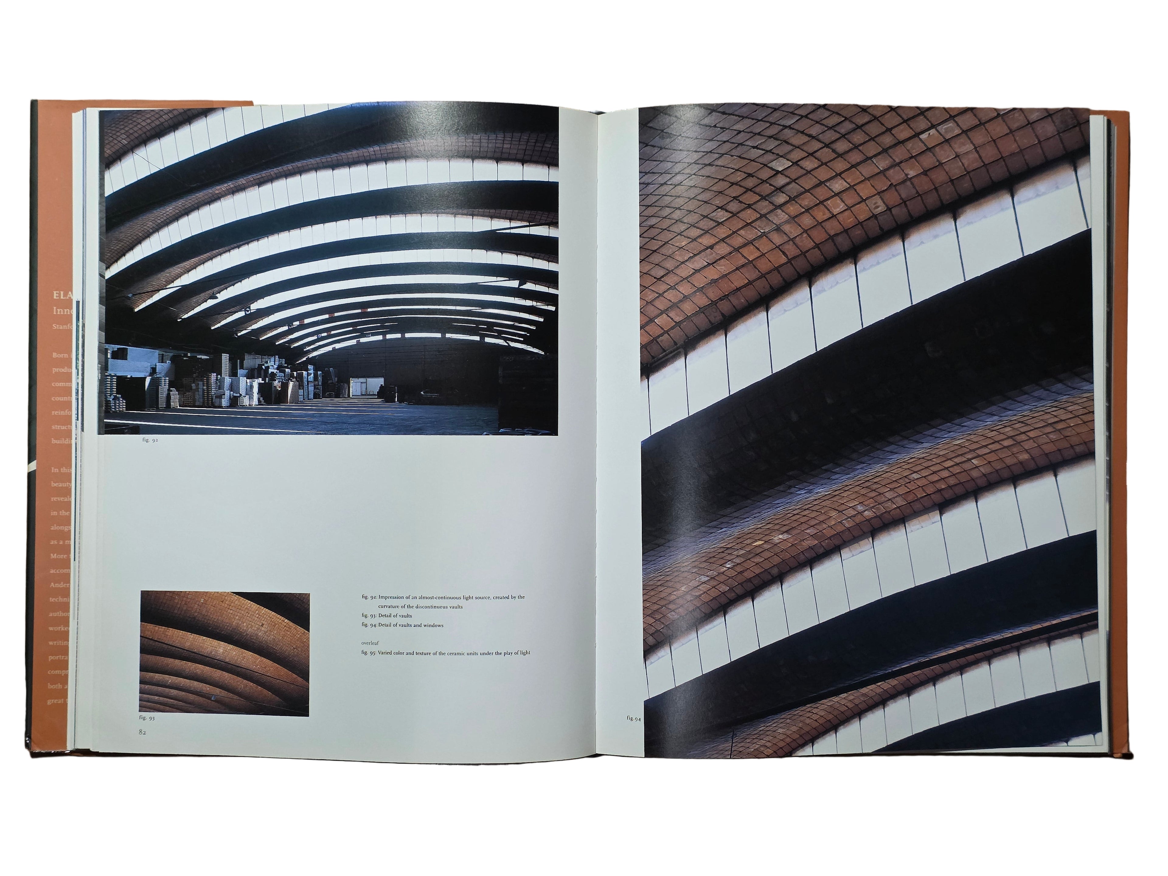 Open book showing architectural images on a wooden surface