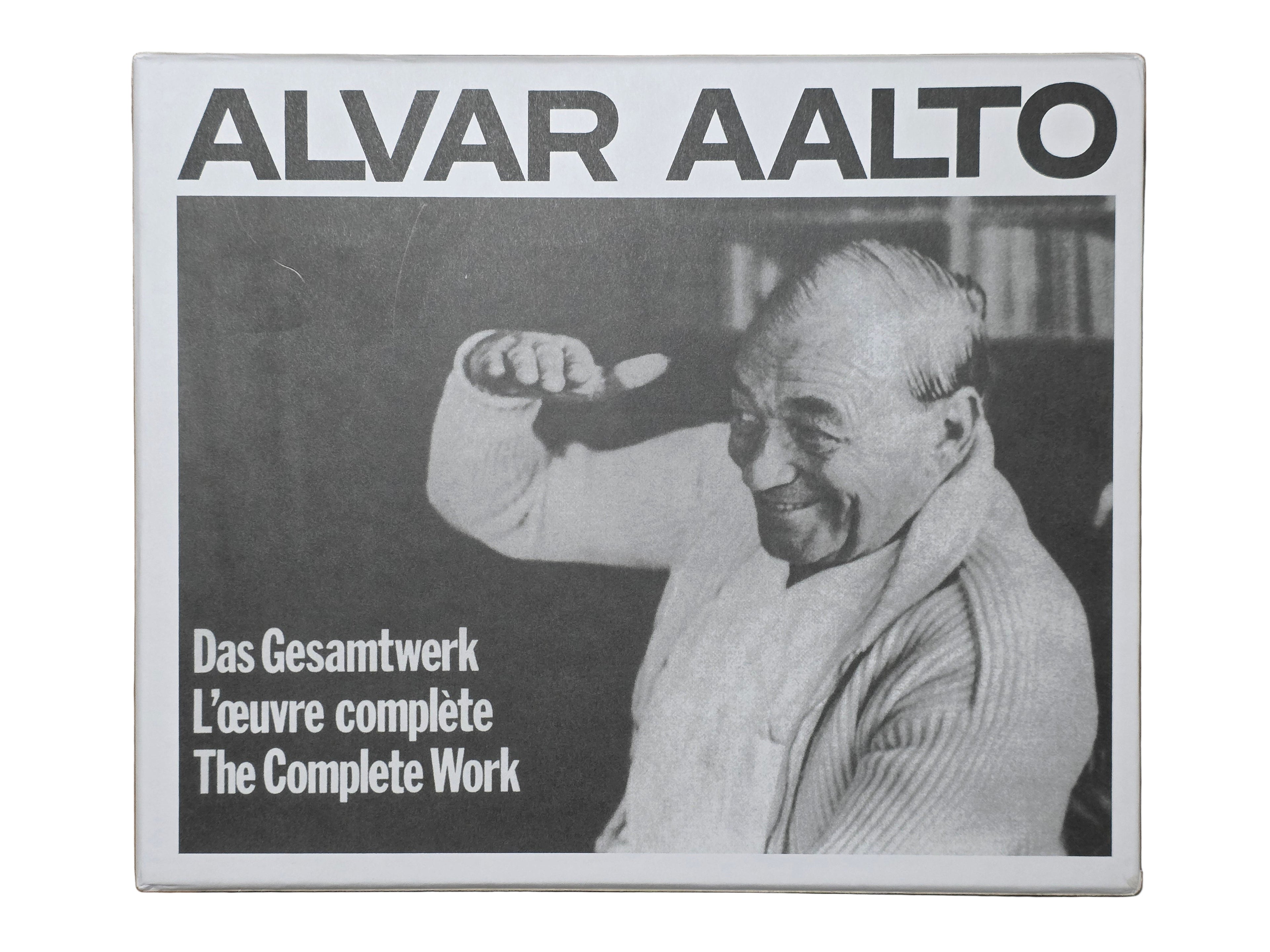 Book cover of 'Alvar Aalto: The Complete Work' with a black and white photo of Alvar Aalto on a wooden surface.